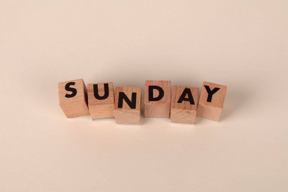 Wooden letter blocks spelling 'Sunday' on a neutral background for weekend concepts.